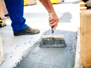 Man concrete waterproofing the floor How Concrete Waterproofing Makes You Money