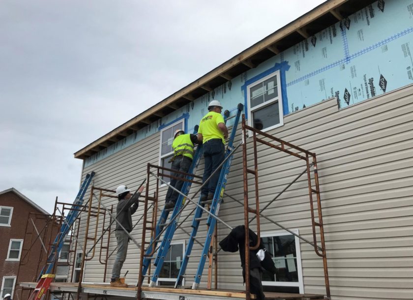 PAINTech employees standing on a ladder renovating a house