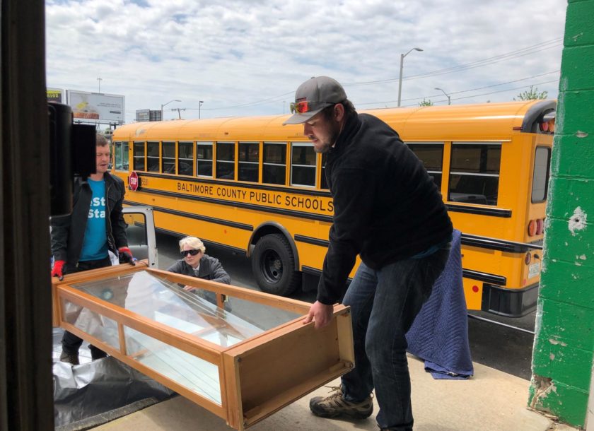 Two employees lifting a glass shelf onto a truck